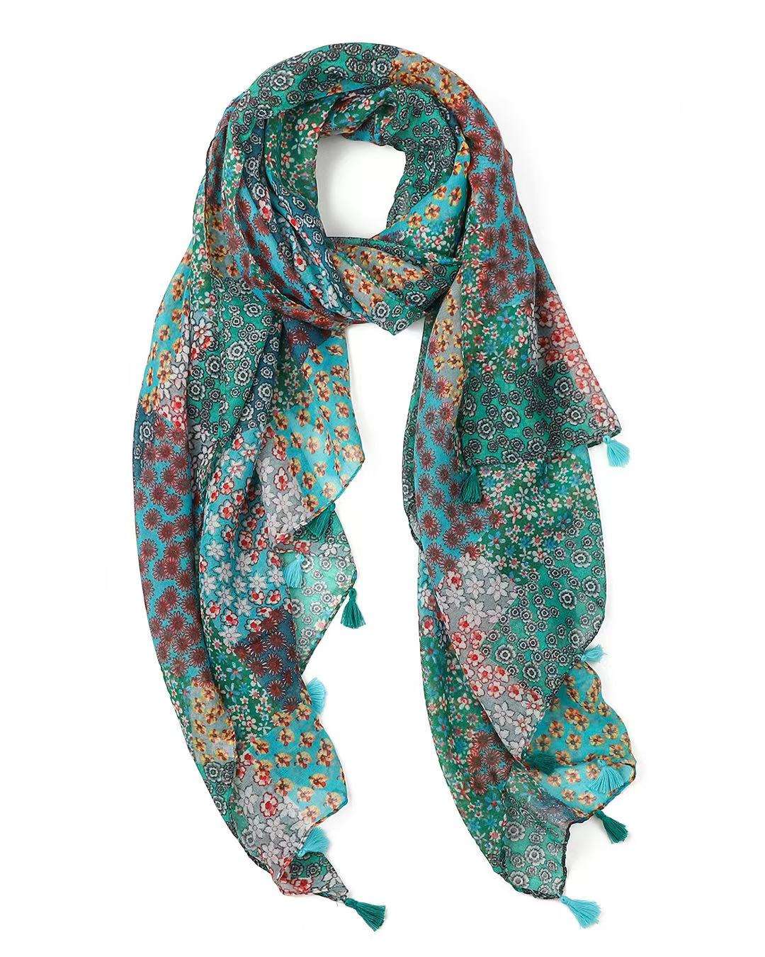 Lightweight scarf in a turquoise and green patchwork of small floral prints, looped to show the teal tassels.