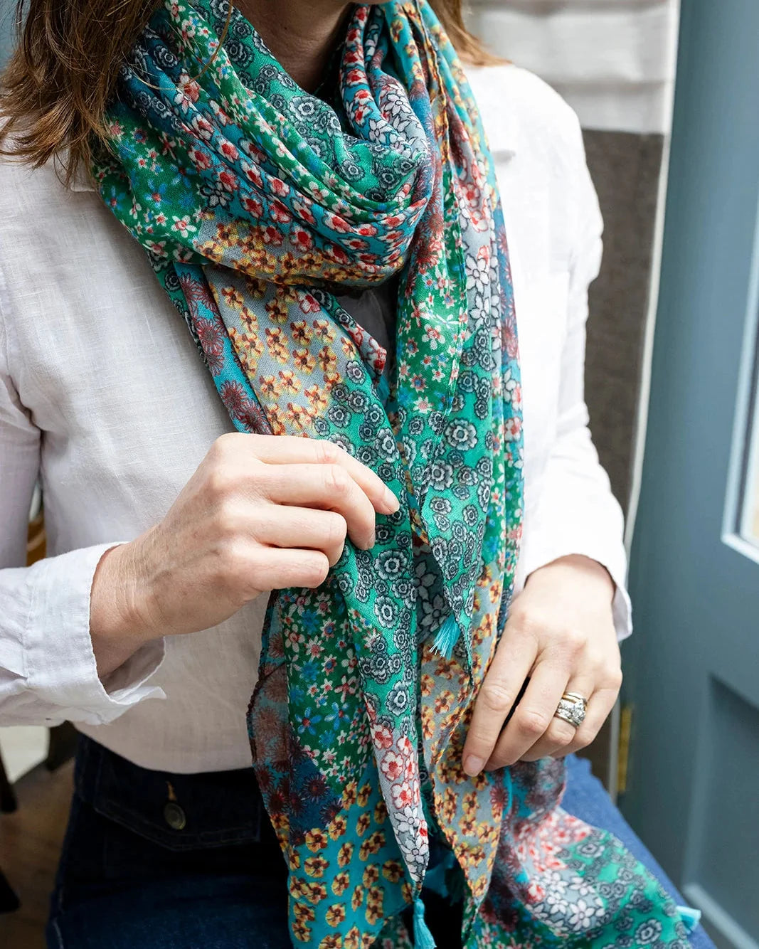 Woman in a white shirt wearing the green patchwork scarf wrapped twice around her neck.