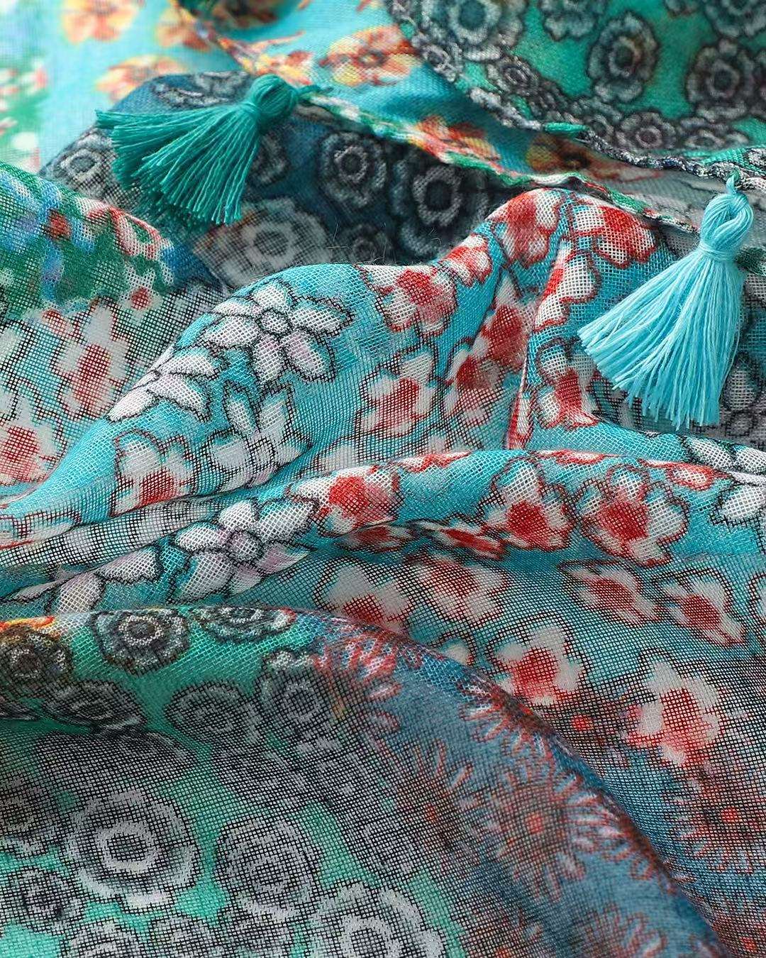 Close-up of the green patchwork scarf showing the turquoise, red and white ditsy floral panels and a teal tassel.