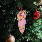 The green Huxter hand cream box hanging by its ribbon on a Christmas tree beside a red bauble.
