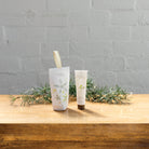 The Citrus hanging hand cream box beside its 30 mL tube on a wooden table with pine sprigs.