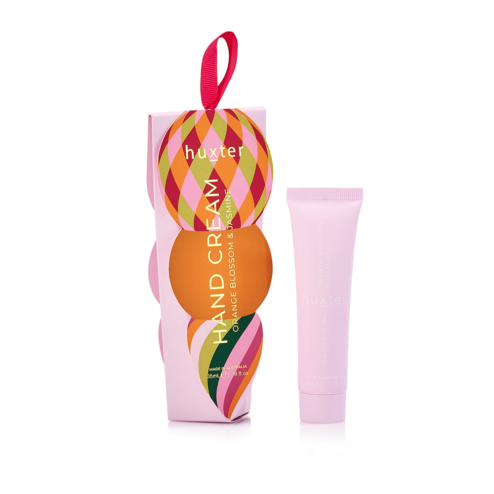 Pink Huxter hanging hand cream box with a diamond-patterned bauble and ribbon loop, beside the pale pink Orange Blossom & Jasmine tube.