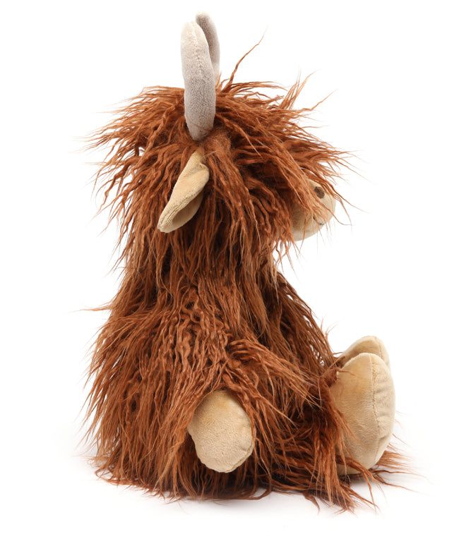 Side view of the cow, its long fur falling over its face and down its back.