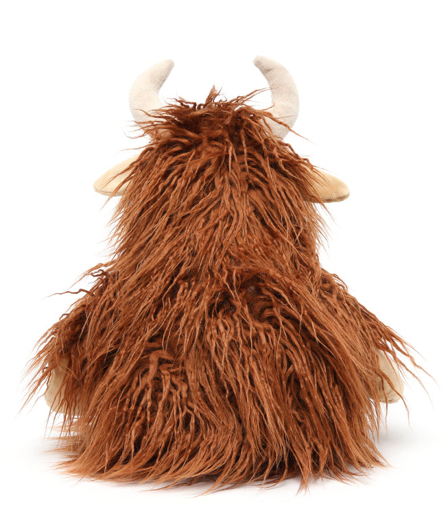 Back view of the cow, all long rust-coloured fur with its cream horns and ears showing.