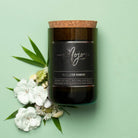 Himalayan Bamboo soy candle in a cork-topped reclaimed wine bottle, styled with white flowers and bamboo leaves