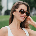 A woman outdoors in a park wearing the Vibe sunglasses, turned to the side