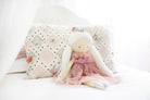 Penelope princess doll seated against cushions on a white bed