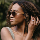 A woman with curly hair in profile wearing the Lila Grace sunglasses