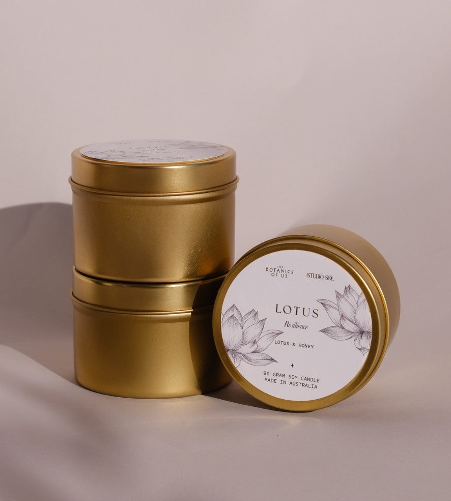 Three gold Lotus travel tins, one tipped forward to show its lid label with a drawing of the lotus.