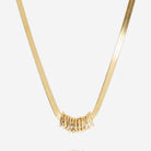 Flat gold snake chain necklace with a cluster of small gold rings threaded at the front.