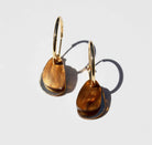 A pair of gold hoop earrings, each hung with a smooth organic teardrop of warm amber and tortoiseshell marbled acrylic over a slim gold mirror panel.