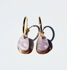 A pair of gold hoop earrings, each hung with a smooth organic teardrop of soft lilac marbled acrylic over a slim gold mirror panel.