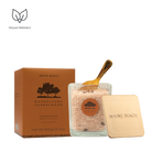 Rangelands Sandalwood Bath Salts in a glass jar with a gold scoop, beside its metal lid and orange box