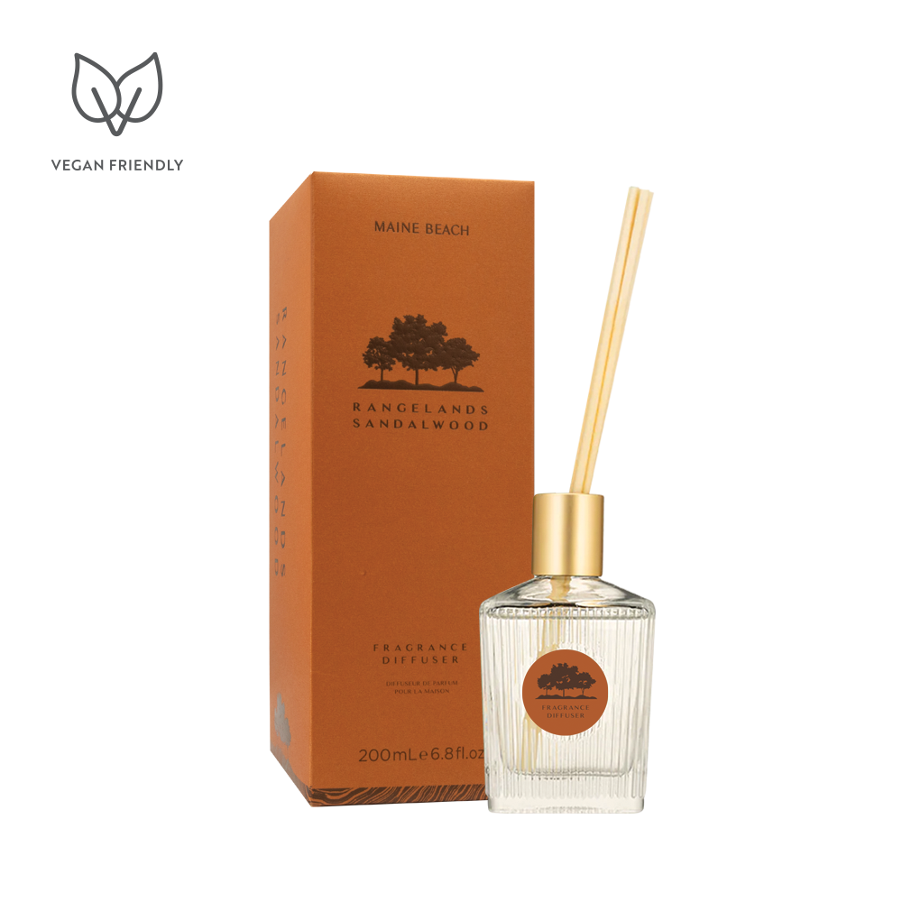 Rangelands Sandalwood Fragrance Diffuser in a glass bottle with a gold top and reeds, beside its orange box