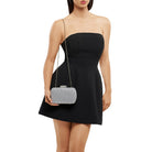 Model in the black strapless dress wearing the silver clutch on its fine chain