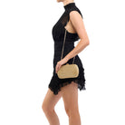 Side view of the model wearing the gold clutch on its chain over her shoulder