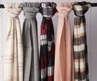 Five merino wool scarves hanging side by side in cream, grey, burgundy check, blush and dark check