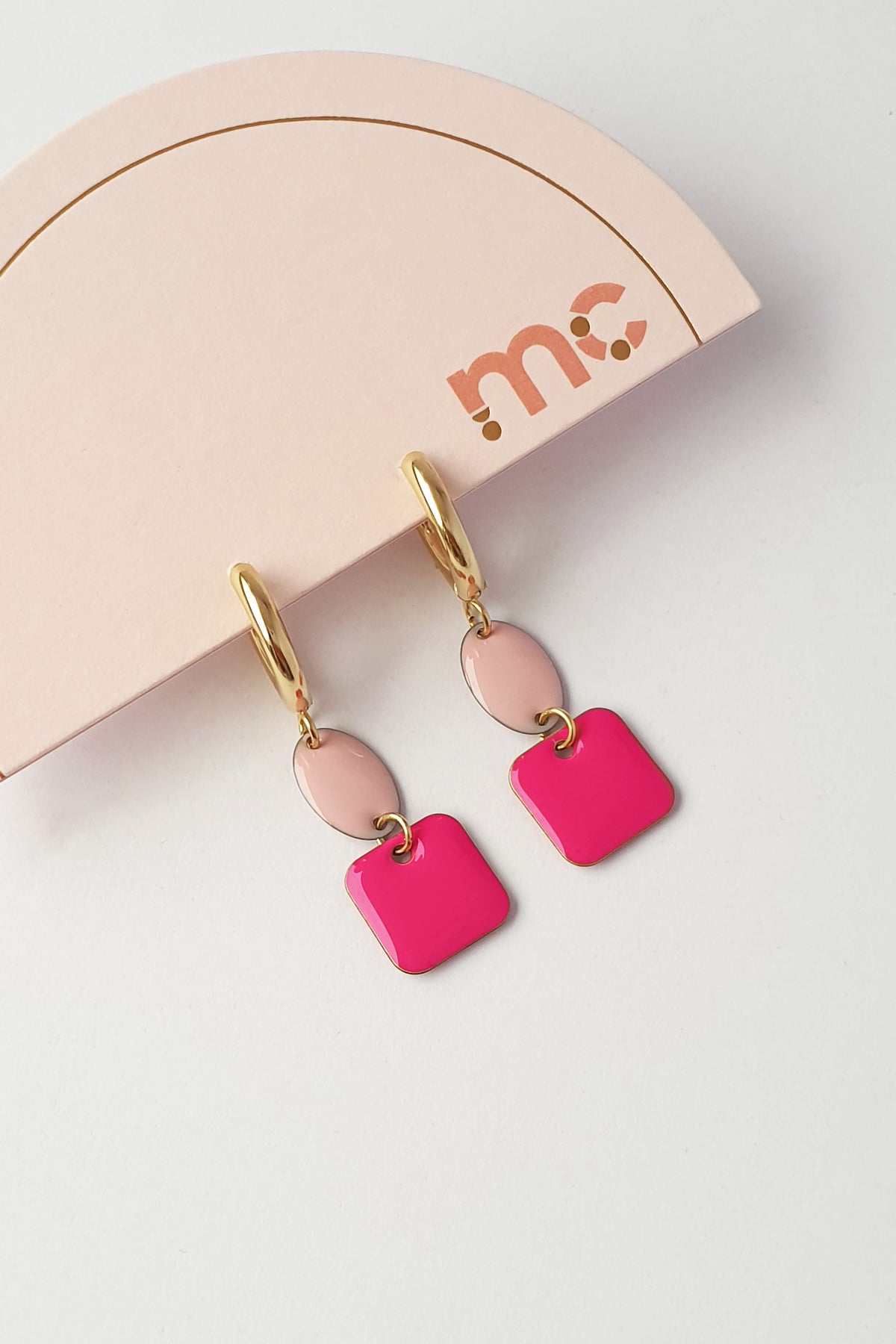 Huggie hoop earrings with two enamel squares below each hoop, soft dusty pink above bright magenta, on a card printed mc.