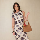 A model in a check dress with the mocha bag hanging from her arm.