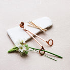 Rose gold wick trimmer on white stone with fresh white flowers