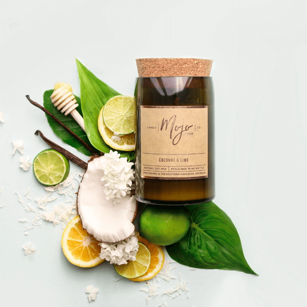 Coconut & Lime candle on white with lime halves, lemon slices, coconut flesh and a honey dipper