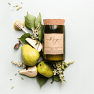 French Pear soy candle in a cork-topped reclaimed wine bottle with fresh pears, blossom and a honey dipper