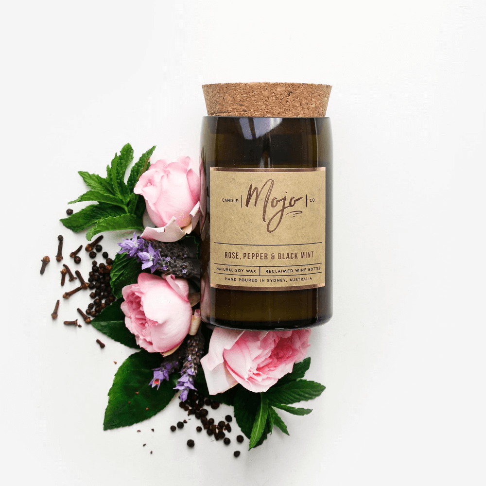 Rose, Pepper & Blackmint soy candle in a cork-topped reclaimed wine bottle with pink roses and lavender