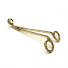 Gold stainless wick trimmer on a cream background