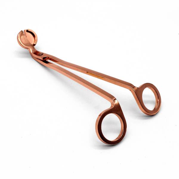 Rose gold stainless wick trimmer on a cream background
