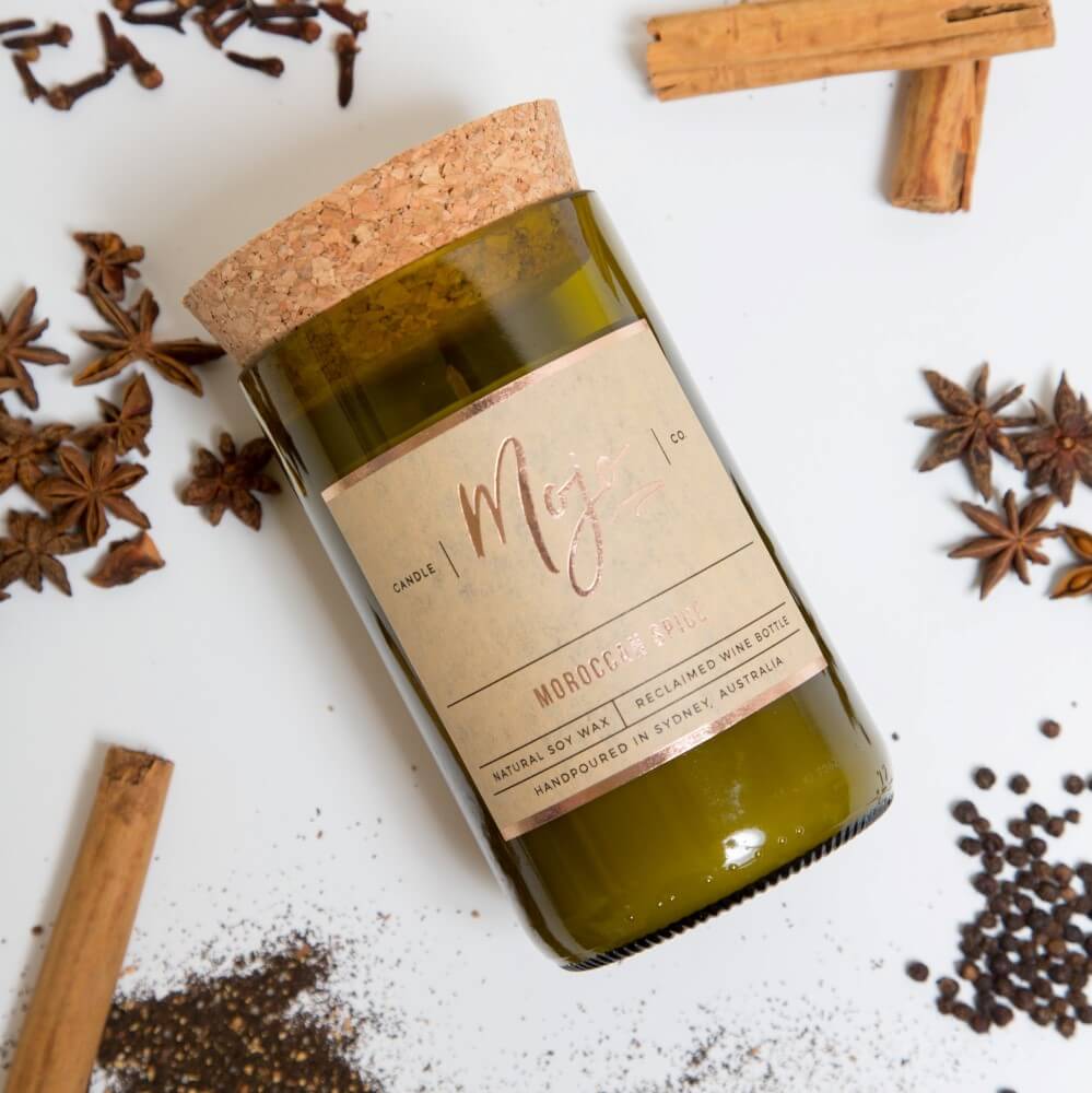Moroccan Spice candle on white with cinnamon sticks, star anise, cloves and scattered tea leaves