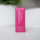 Slim pink box of Raspberry Fields lip balm standing on a white surface.