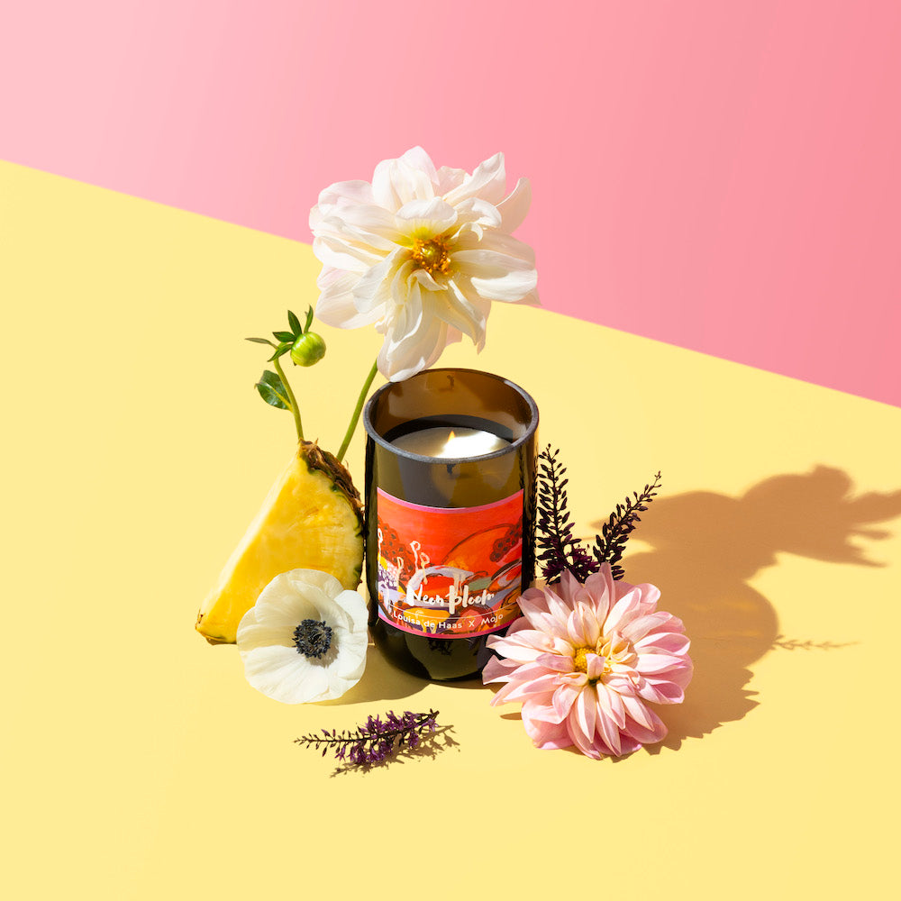 Neon Bloom candle on a pink and yellow backdrop with pineapple and dahlias