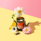 Neon Bloom candle on a pink and yellow backdrop with pineapple and dahlias