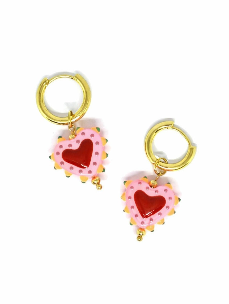 Pair of gold-tone huggie hoops, each with a pink heart charm dotted in deeper pink, a red heart in the middle and orange points around the edge