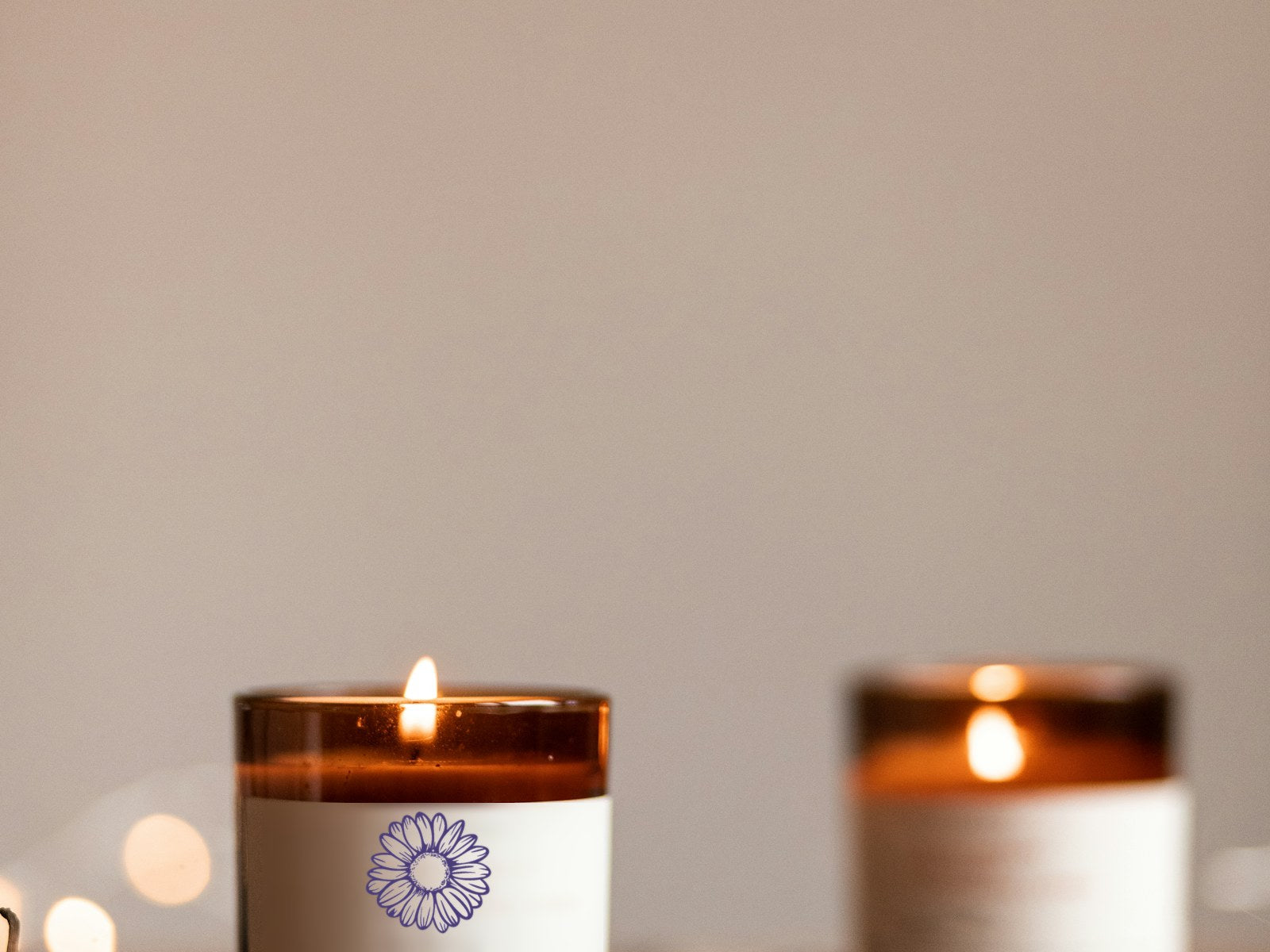 Lit amber jar candle with Purple Merchant daisy label