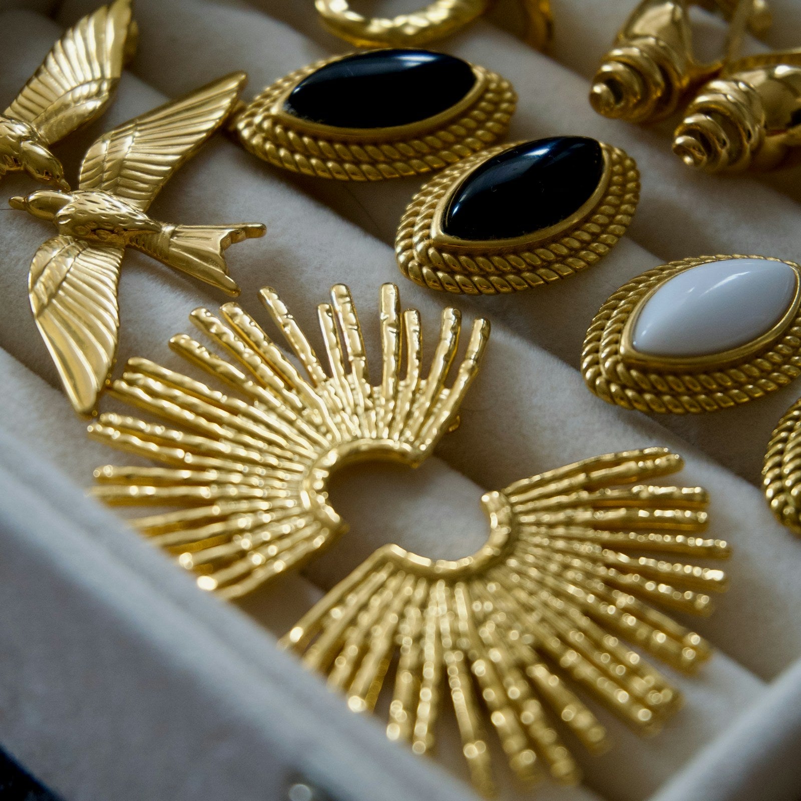 Gold statement earrings displayed in a jewellery tray, macro