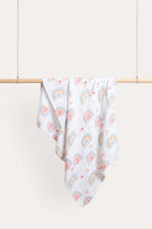 Rainbow muslin wrap hanging over a timber rail, printed with watercolour rainbows and small red hearts on white.
