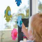 Child spinning daisy and rocket spinners stuck to a window