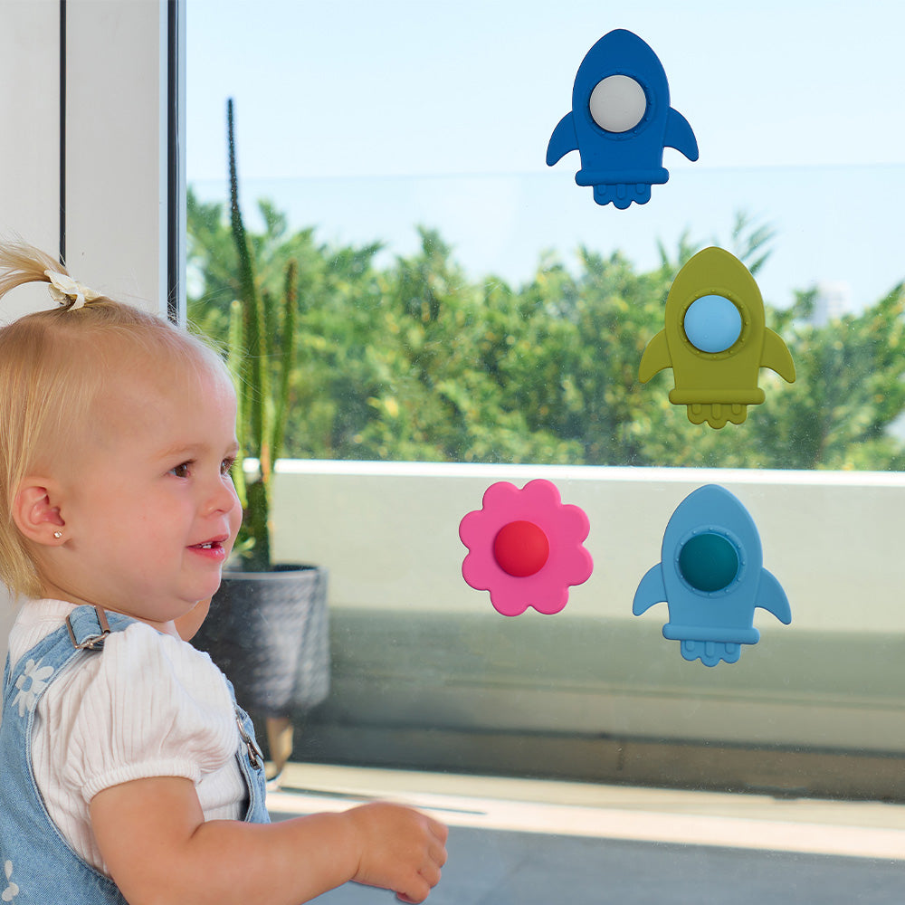 Toddler by a window with daisy and rocket spinners stuck to the glass