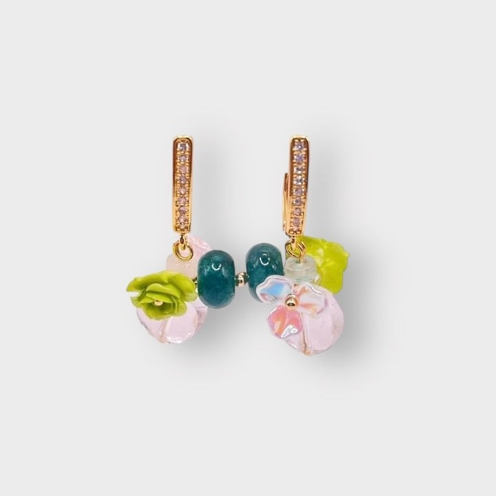 Rosarium grape earrings in Green: gold pavé huggie hoops hung with teal beads, lime green roses and pale pink glass flowers, on a pale grey background.