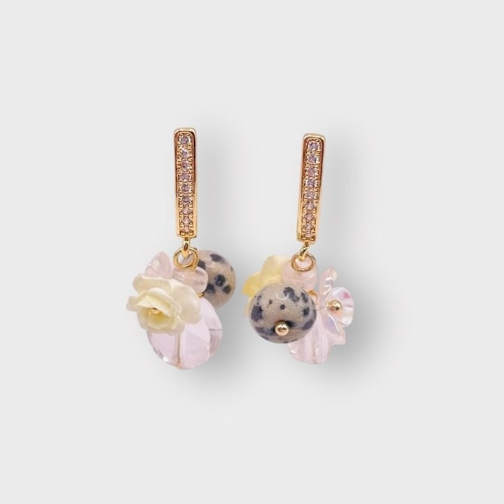 Rosarium grape earrings in Grey: gold pavé huggie hoops hung with speckled grey stone beads, cream roses and pale pink glass flowers, on a pale grey background.