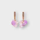 Rosarium grape earrings in Mauve: gold pavé huggie hoops hung with lilac beads, pale pink glass flowers and a lilac rose, on a pale grey background.