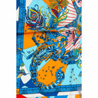 Close-up of the Astro Scorpio silk scarf - an ornately patterned blue scorpion with peacock feathers, stars and orange panels