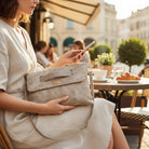 Woman at a café table resting her hand on the latte ShineEdge carrier in her lap