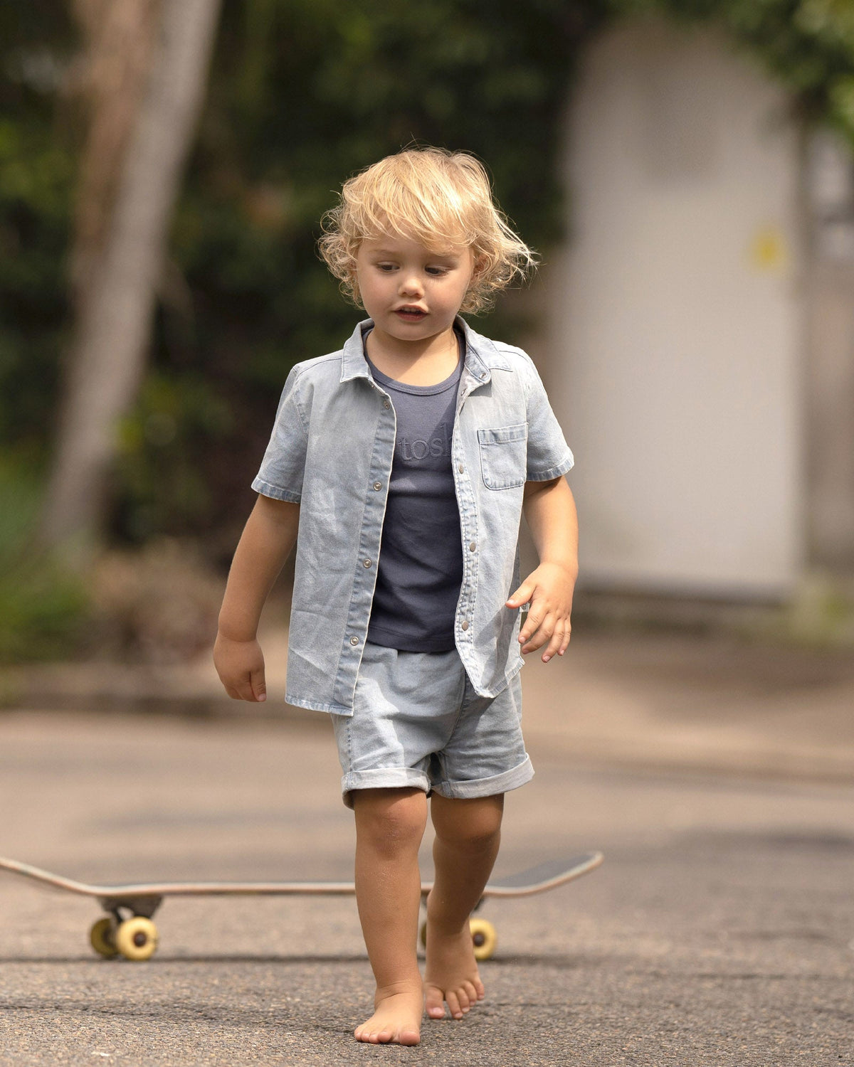 Toddler walking past a skateboard in the Indiana shirt worn open over a navy tee, with the Indiana shorts