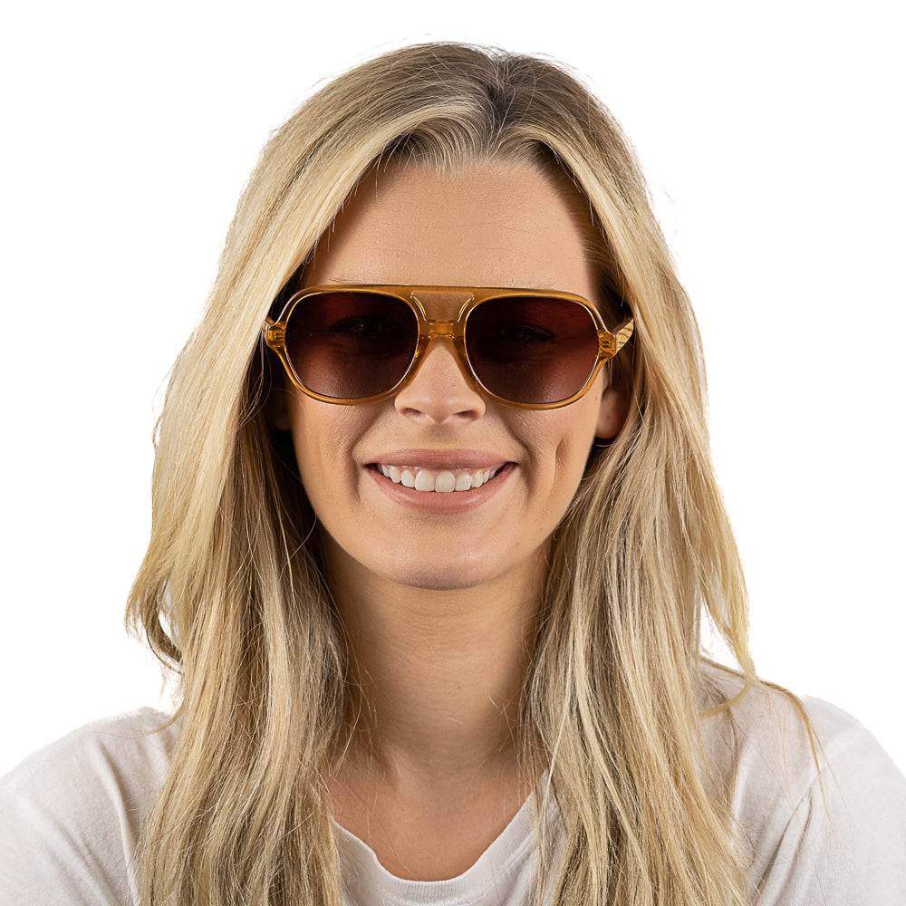 A woman with long blonde hair smiling, wearing the Billy sunglasses