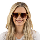 A woman with long blonde hair smiling, wearing the Billy sunglasses