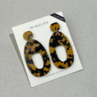 A pair of large tortoiseshell acrylic clip-on earrings on a white Mingled card marked Clip-On, each a wide open shape hung from a small rounded top.