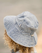 Child with curly hair, seen from behind, wearing the washed blue Indiana sunhat