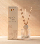 The Sweet Pea reed diffuser, a ribbed glass bottle with natural reeds, beside its cream box.